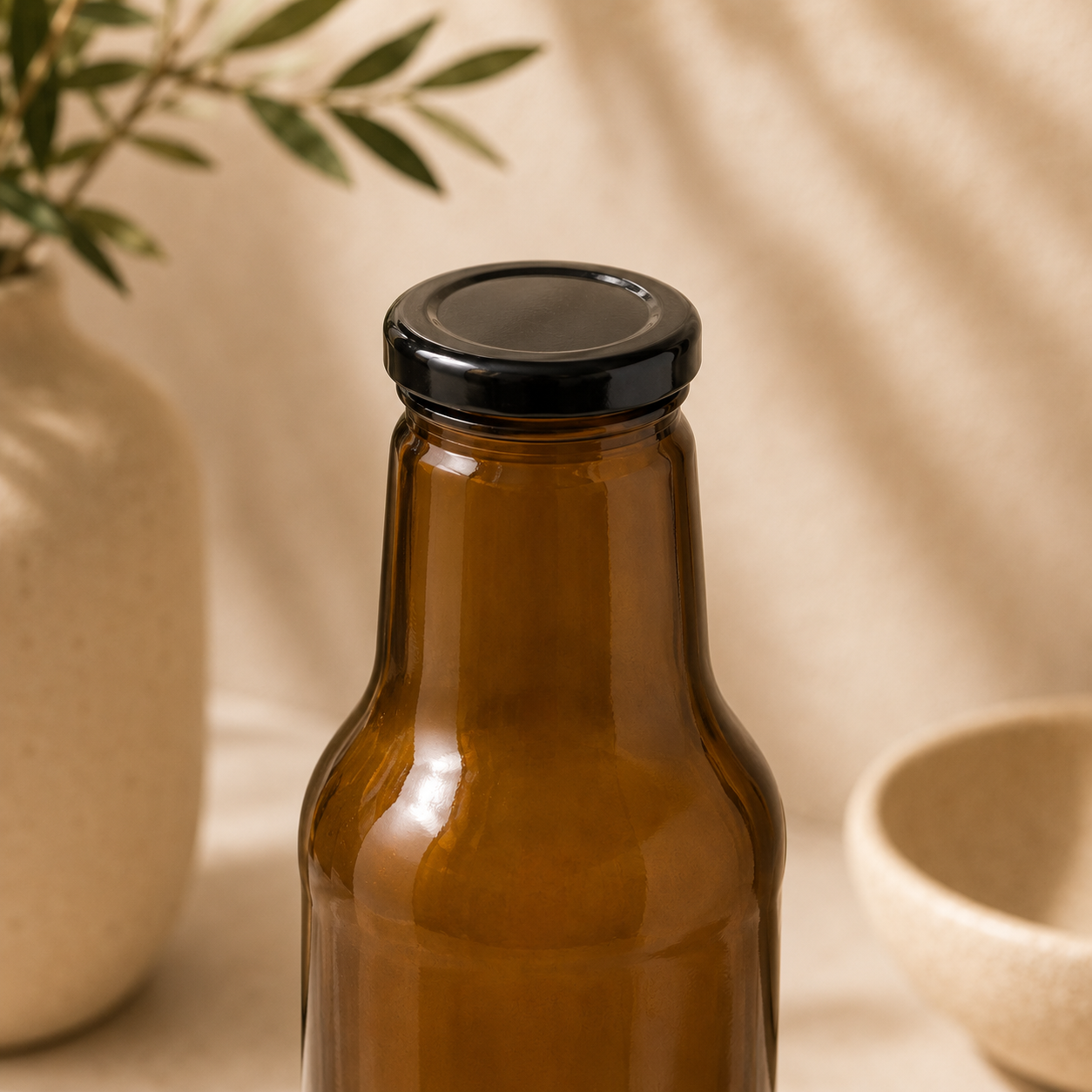 Braune Weithalsflasche mit schwarzem Twist-Off-Verschluss in einer warmen, beigen Produktkulisse.