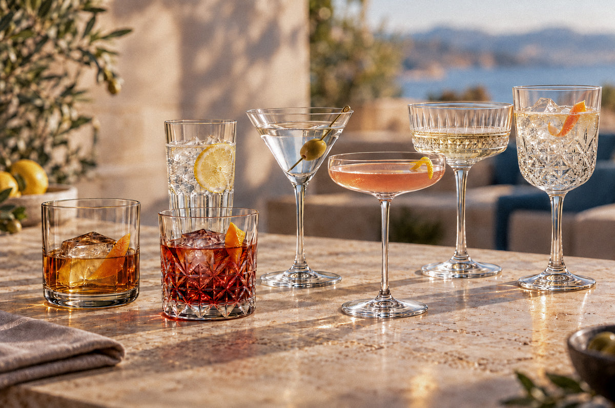 Auswahl eleganter Trinkgläser für Whisky, Longdrinks, Cocktails und Champagner in stilvoller, sonniger Bar-Atmosphäre